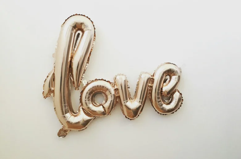 Золотий повітряний шар з написом love на білому фоні.