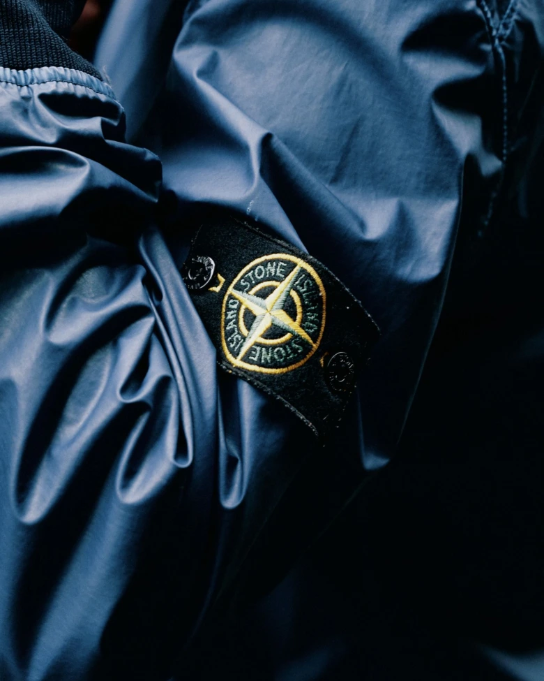 Логотип Stone Island на рукаві темно-синьої куртки.