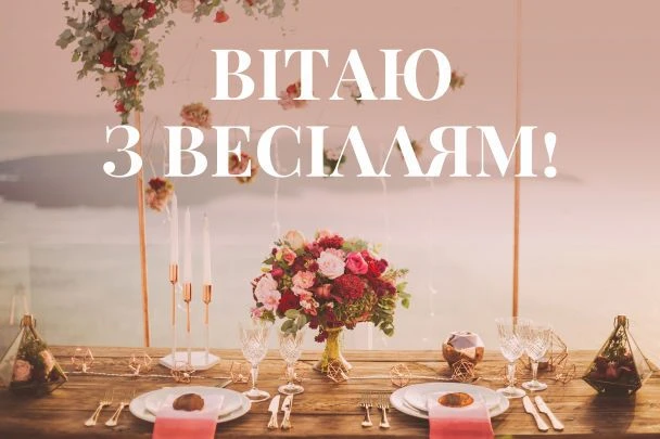 Весільний стіл з квітами та привітанням українською мовою.